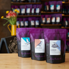 Kaffeetüten mit Espresso, Omniroast und Filterkaffee vor Kaffeeregal im Café